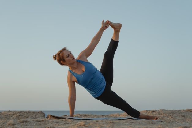 Těhotná žena cvičí na pláži jógu. 